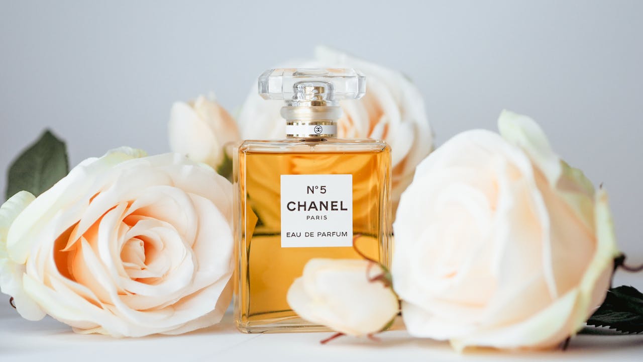 why-choose-us Chanel No 5 perfume bottle surrounded by elegant white roses, symbolizing luxury and femininity.